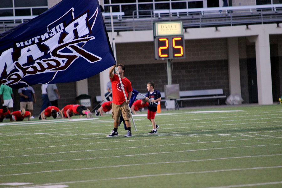 Captain Zach Farmer waves the school flag while the rest of Honor Guard does pushups to celebrate a touchdown during varsity's first game on Sept 1.